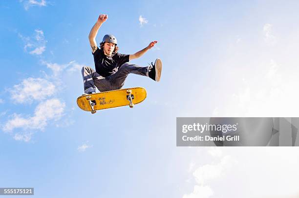 usa, florida, west palm beach, man jumping on skateboard against sky and clouds - skateboard foto e immagini stock