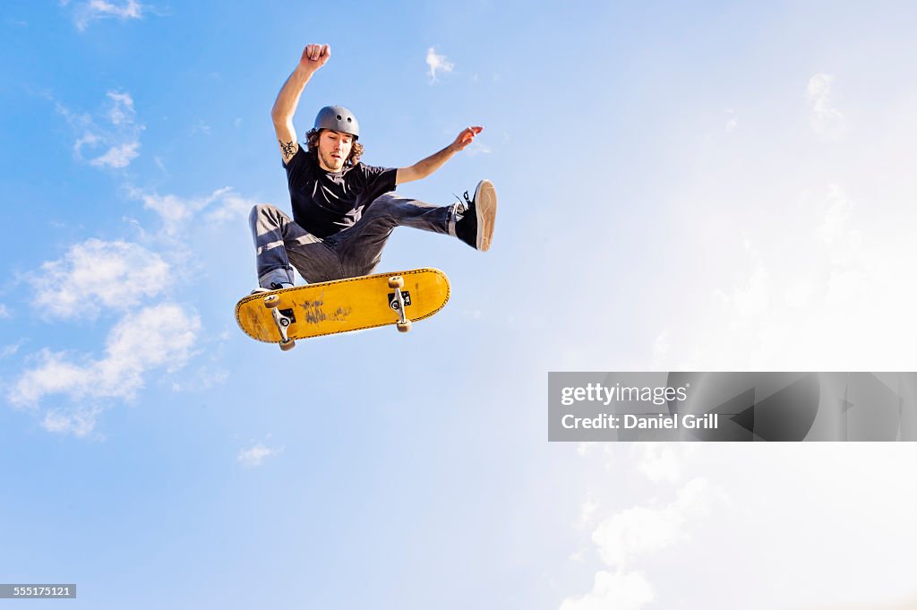 USA, Florida, West Palm Beach, Man jumping on skateboard against sky and clouds