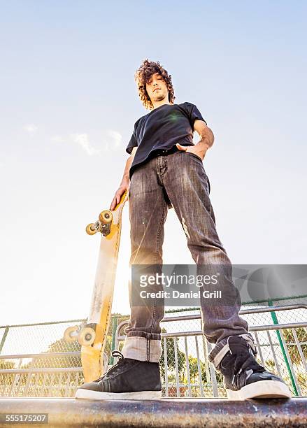 usa, florida, west palm beach, man leaning on skateboard in skatepark - low angle view stock pictures, royalty-free photos & images