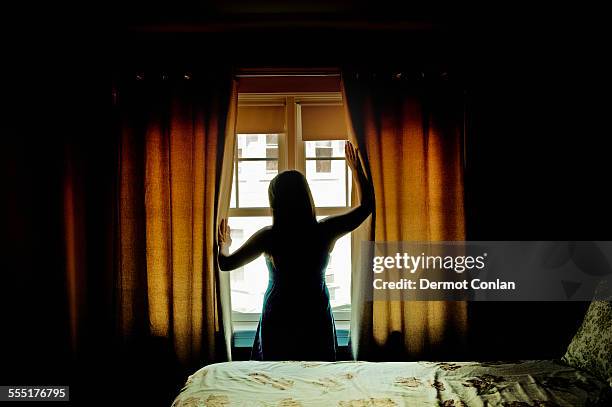 usa, massachusetts, boston, rear view of female opening curtains at bedroom window - close to stock pictures, royalty-free photos & images