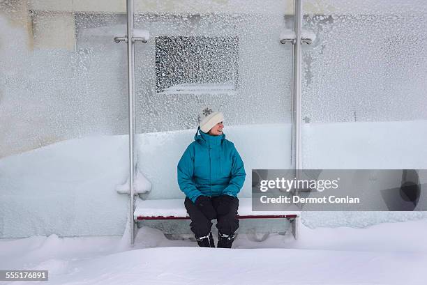 usa, massachusetts, boston, middle aged woman sitting in bus stop, winter snow - bus shelter stock pictures, royalty-free photos & images