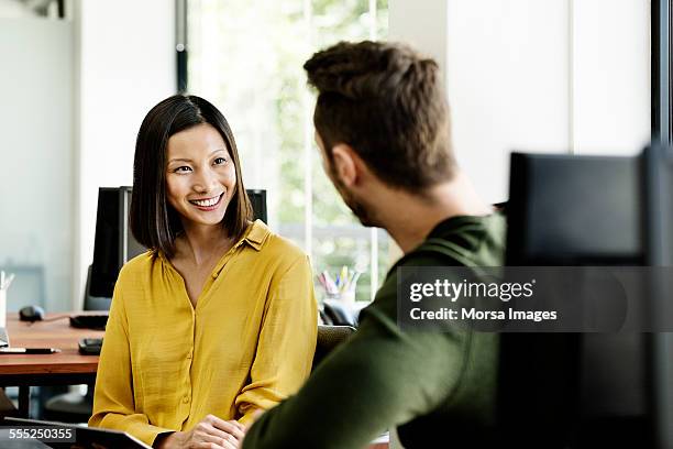 businesswoman discussing with colleague in office - man blouse stock pictures, royalty-free photos & images