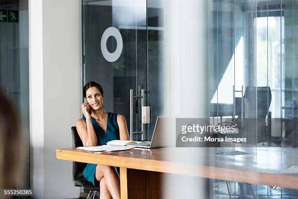 businesswoman using mobile phone at desk - pernas cruzadas imagens e fotografias de stock