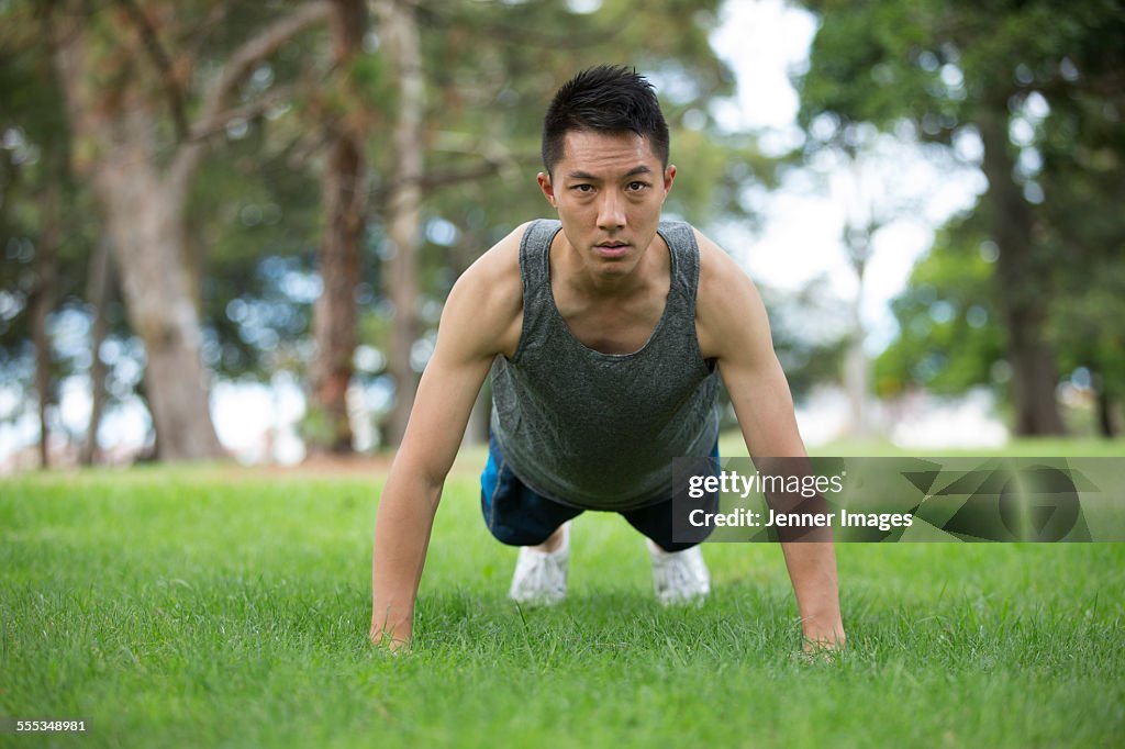 Asian man doing push up exercise in park.