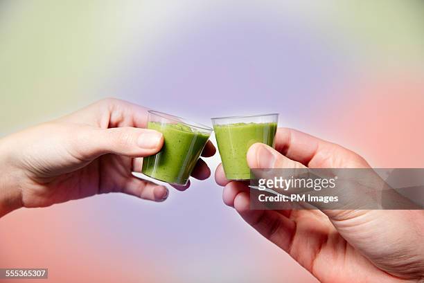 toasting with wheat grass smoothies - wheatgrass stock pictures, royalty-free photos & images