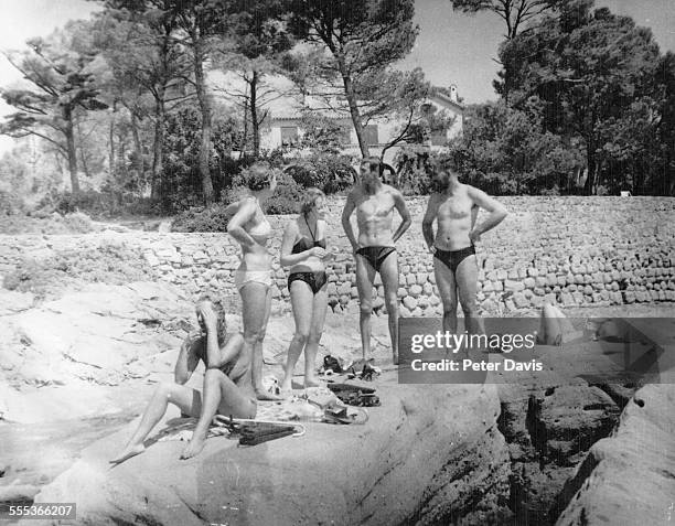 British career criminal Bruce Reynolds , his girlfriend, and another unidentified couple, all in swimsuits, stand on a boulder while in vacation in...