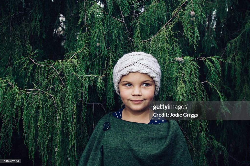 Portrait of girl standing in front of pine tree
