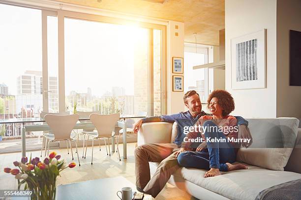 40's couple in apartment - couple in modern living room stock pictures, royalty-free photos & images