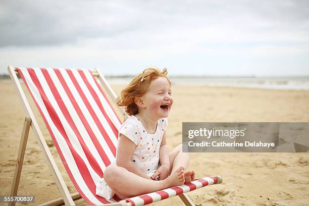 a girl on a deckchair on the beach - barefoot redhead ストックフォトと画像