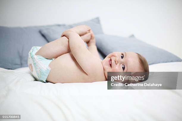 a 8 months old baby laying on a bed - diaper boy fotografías e imágenes de stock