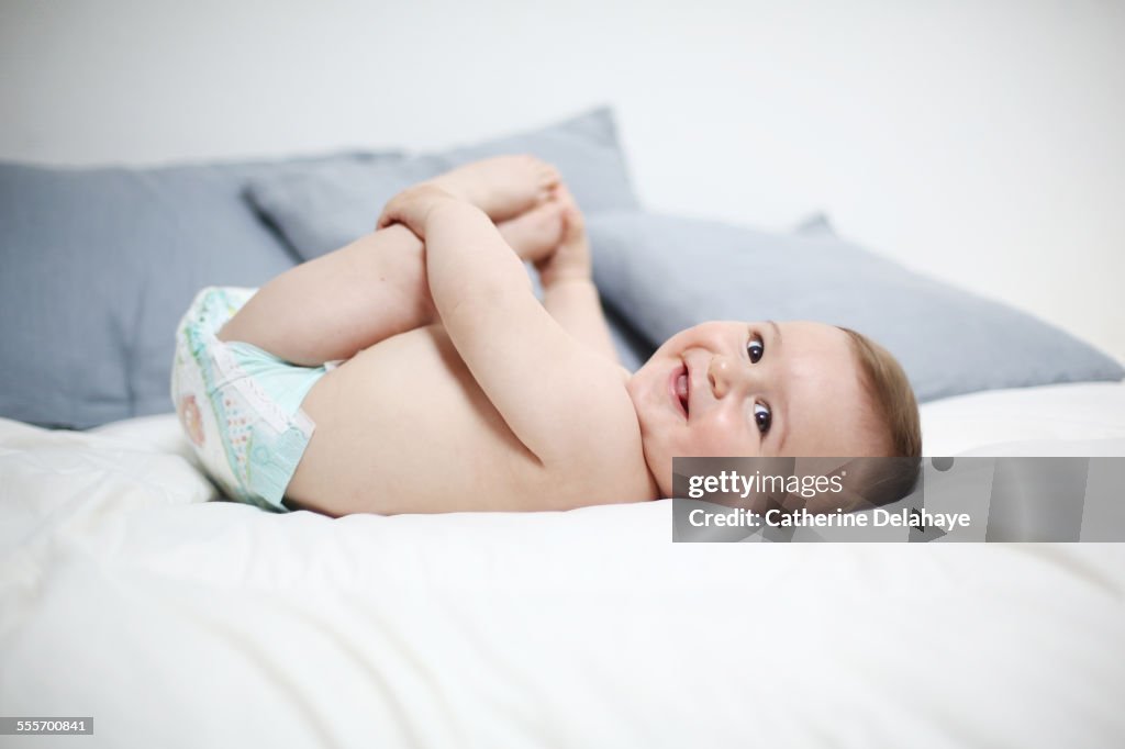 A 8 months old baby laying on a bed