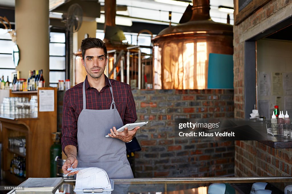 Waiter at microbrewery holding digital tablet