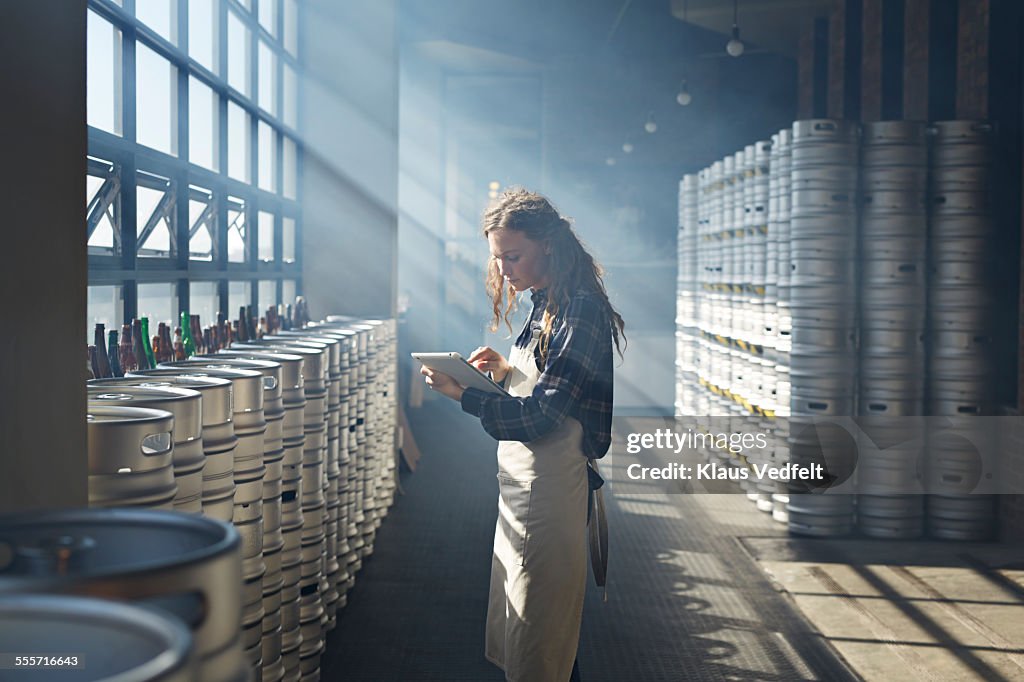 Female waiter counting beer keg's using tablet