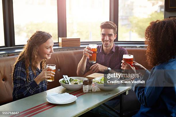 friends drinking beer and laughing at restaurant - artisanal food and drink stockfoto's en -beelden