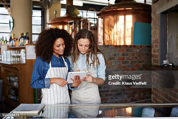 two waiters looking at booking on tablet - restaurateur photos et images de collection