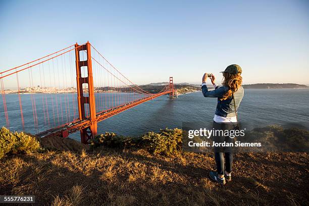 a female taking a iphone picture - golden gate bridge stockfoto's en -beelden
