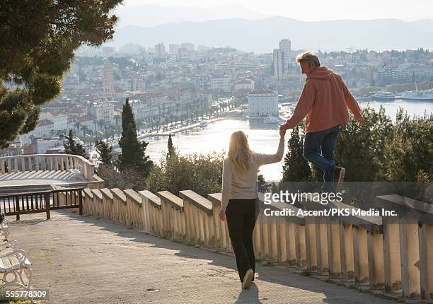 woman provides hand to man on railing above town - split croatia ストックフォトと画像