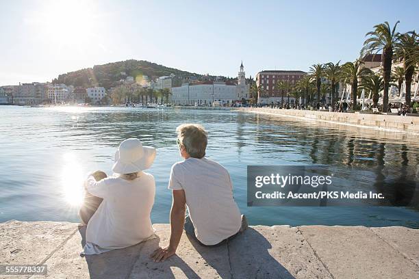 couple relax by water's edge, on marble pier - split stock-fotos und bilder
