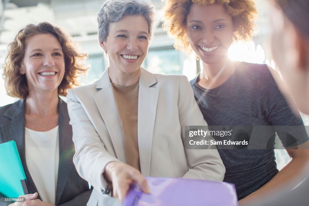 Three smiling businesswomen holding documents