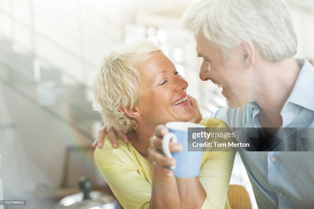 Un couple plus âgé s’embrasse avec une tasse de café