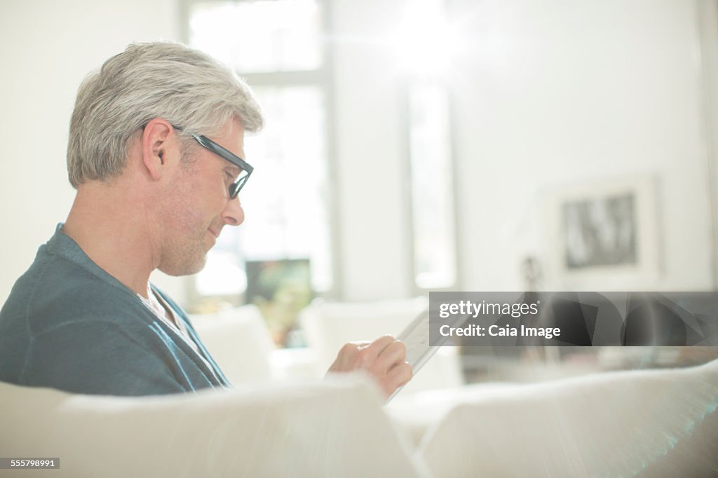Older man using digital tablet on sofa
