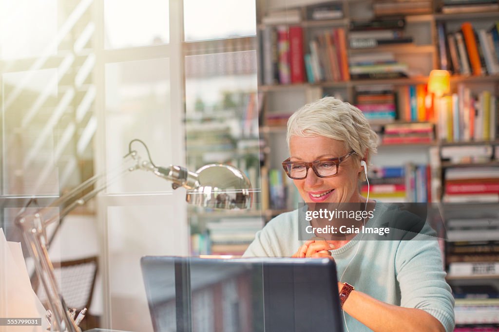 Businesswoman listening to earbuds and working in home office