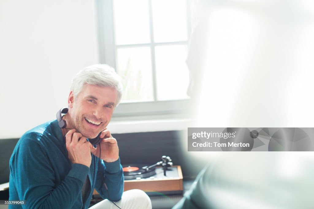 Older man listening to turntable with headphones