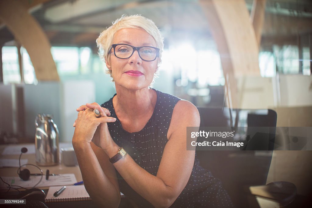 Businesswoman sitting with hands clasped at office desk