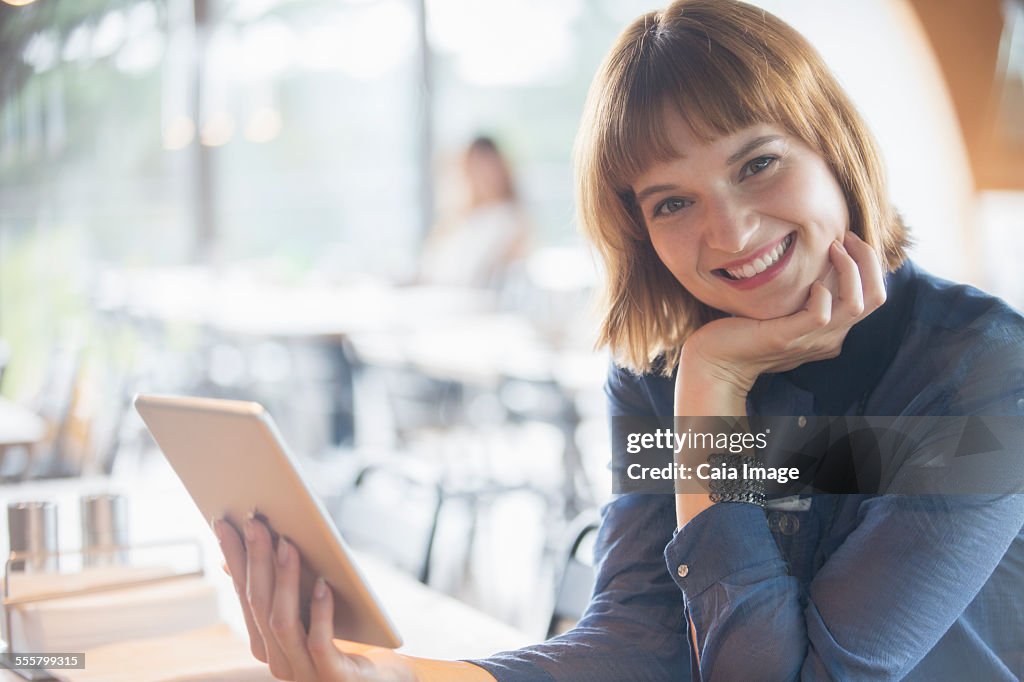 Businesswoman using digital tablet in cafeteria