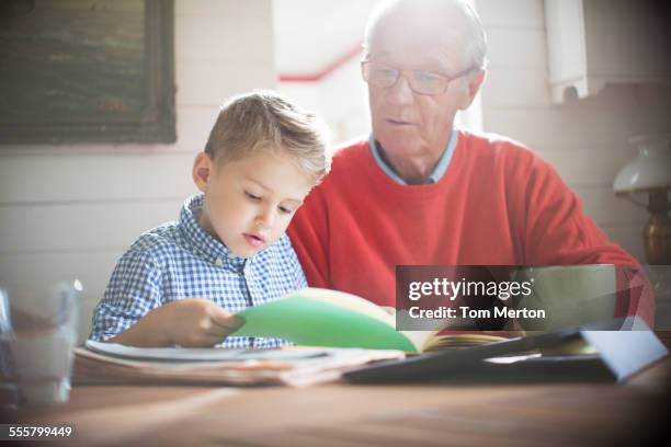 Garçon lisant avec grand-père à table