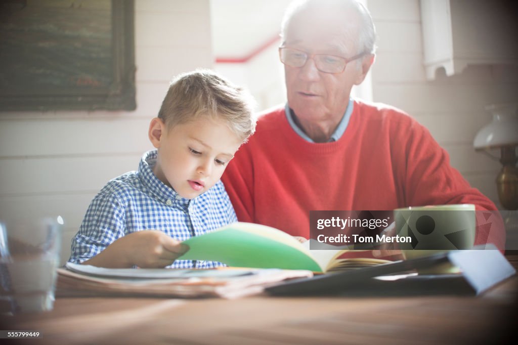 Ragazzo che legge con il nonno a tavola