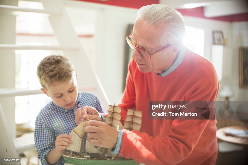 Grandfather and grandson building model sailboat