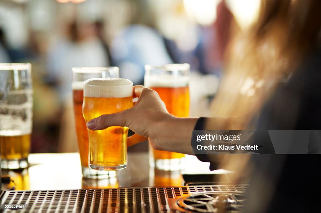 Close-up of bartender serving beers at bar
