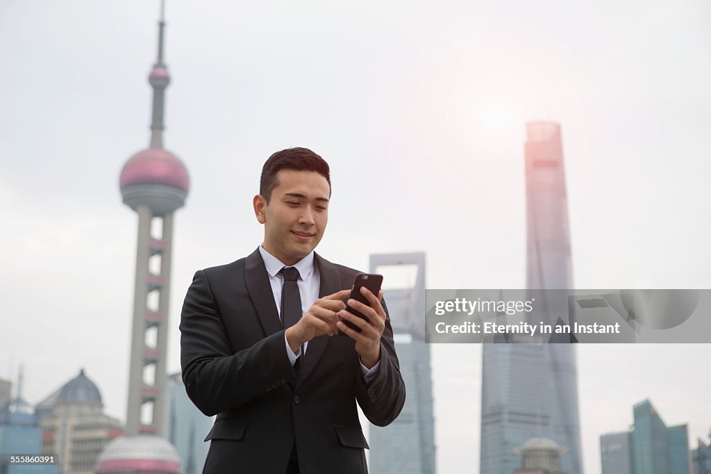Businessman using phone with Shanghai cityscape