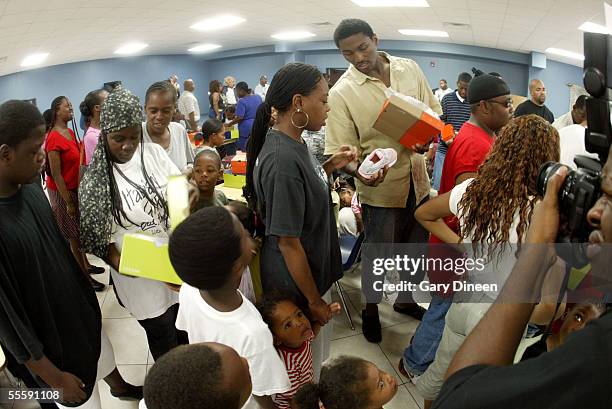 Ron Artest of Indiana Pacers helps an evacue find a pair of shoes for people who have been displaced due to the effects of Hurricane Katrina during...