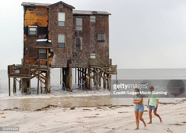People walk on the beach of North Topsail, where several houses now stand in ocean water, on September 15, 2005 in North Topsail, North Carolina....