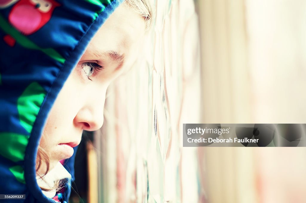 Small, sad girl looking out of window