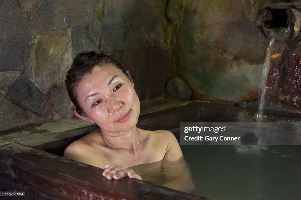 Woman relaxes in hot spring bath