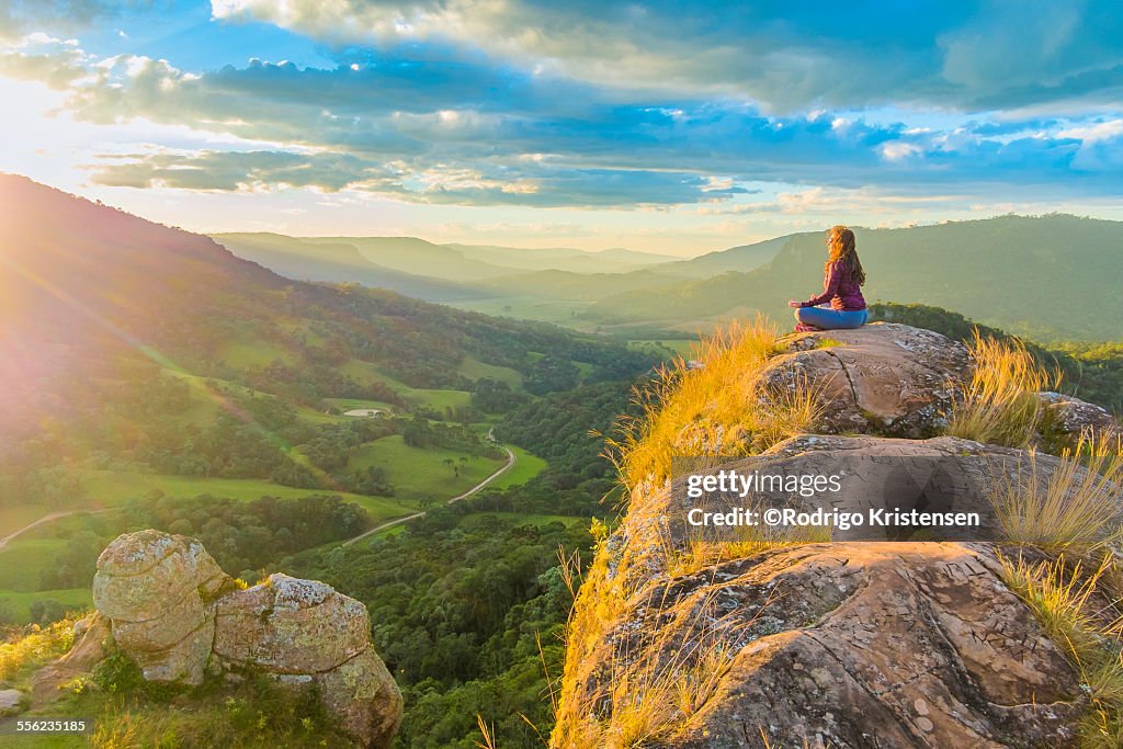 Woman doing yoga on top of the mountains.