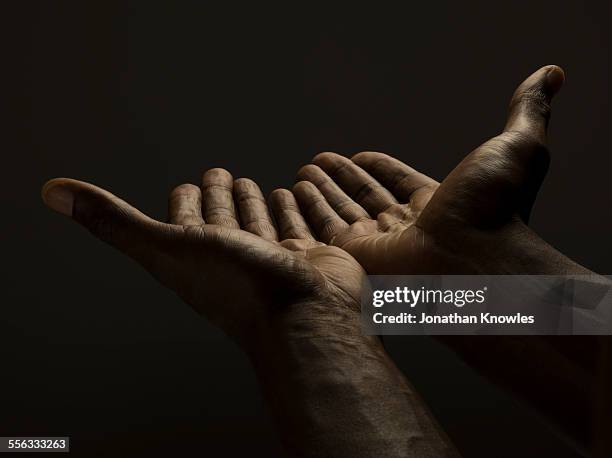 close up of male hands reaching out, dark skin - vrijgevigheid stockfoto's en -beelden