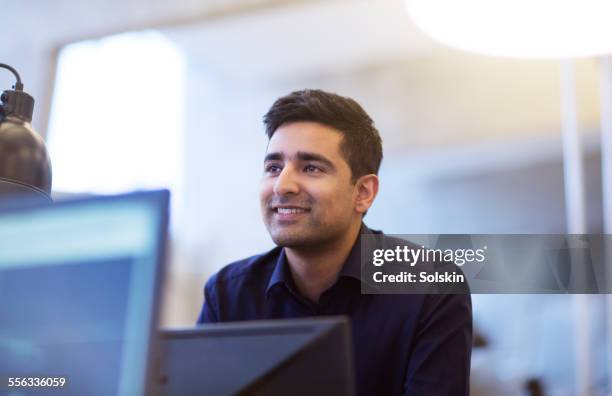 man in office behind computer screens - male looking content stockfoto's en -beelden