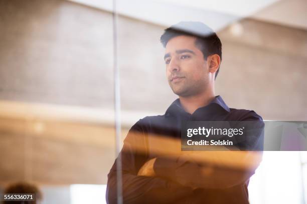 man in office, standing behind glas wall - glass reflection in office stock-fotos und bilder