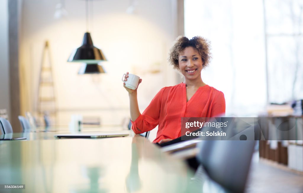 Woman in office taking a break, drinking coffee