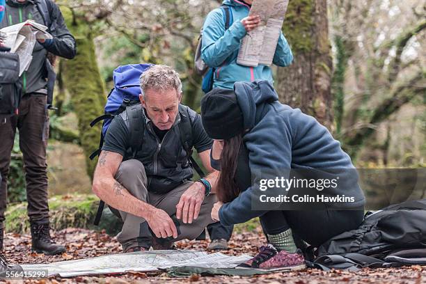 mature man and young woman studying map - orientierungslauf landkarte gruppe stock-fotos und bilder