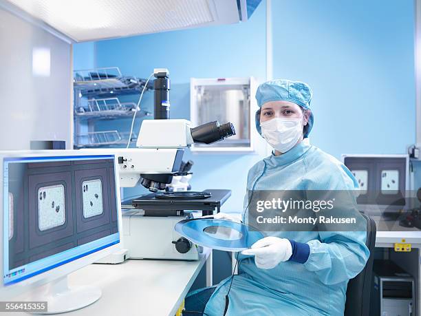 electronics worker in clean room with silicon wafer, portrait - cleanroom stock-fotos und bilder