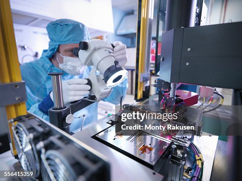 Electronics worker checking component in clean room Electronics worker checking component in clean room