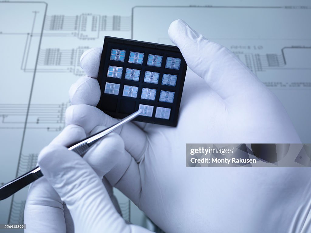 Gloved hands holding small electronic chips in laboratory, close up