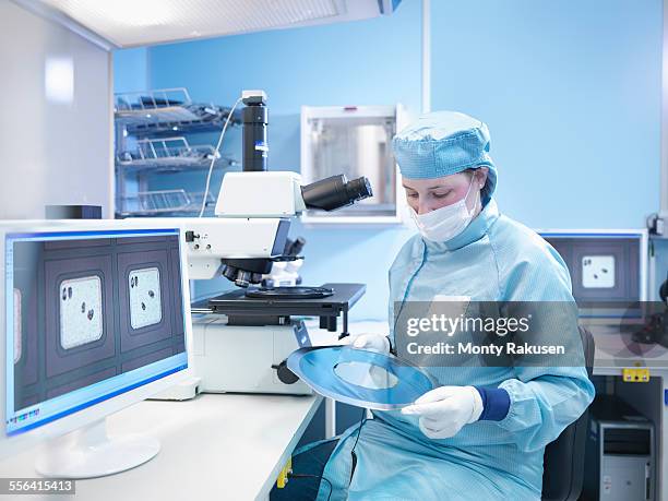 electronics worker in clean room with silicon wafer - cleanroom stock pictures, royalty-free photos & images