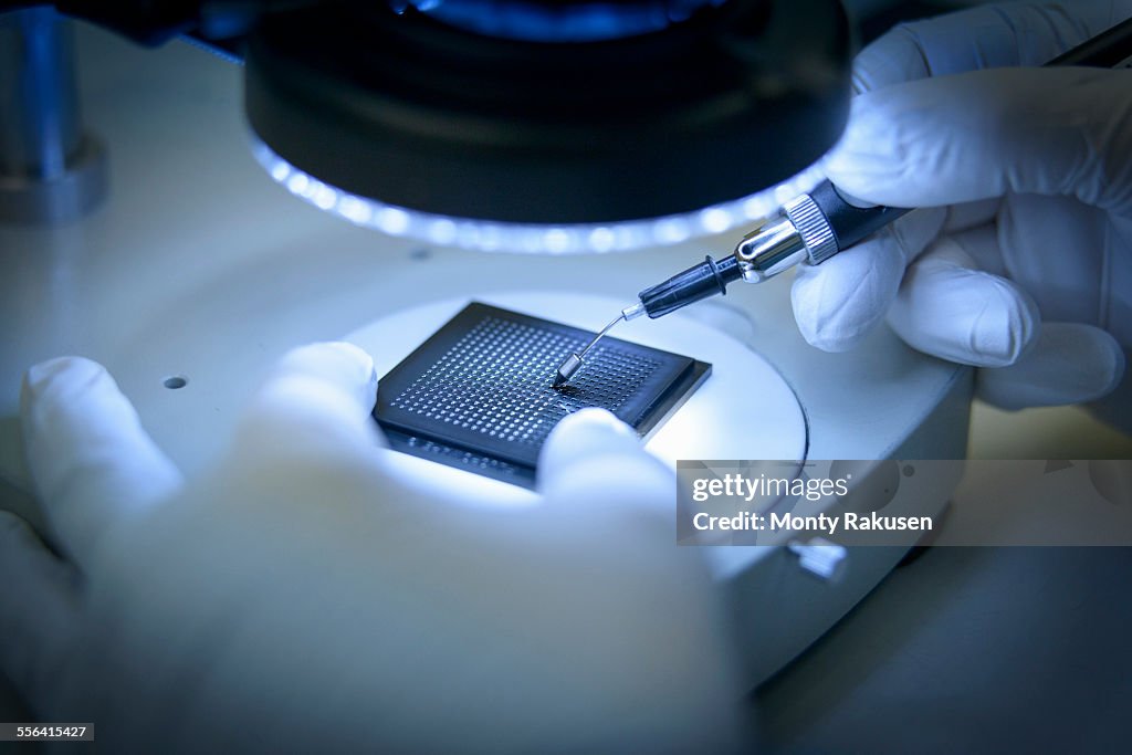 Electronics worker checking small electronic chips in clean room laboratory, close up