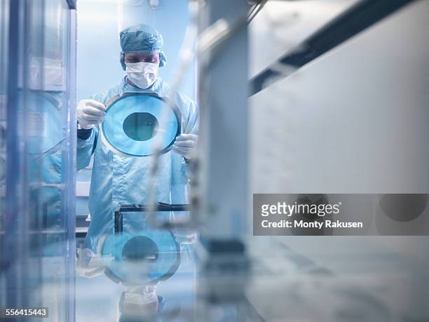 electronics worker holding silicon wafer by cutting machine in clean room - 半導体 ストックフォトと画像